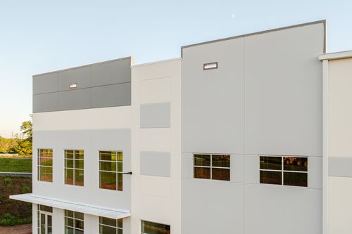 Angled view of a long warehouse facade with alternating white and gray metal panels