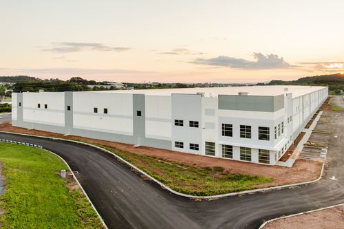 Aerial view of a sprawling white warehouse building with landscaped grounds at sunset