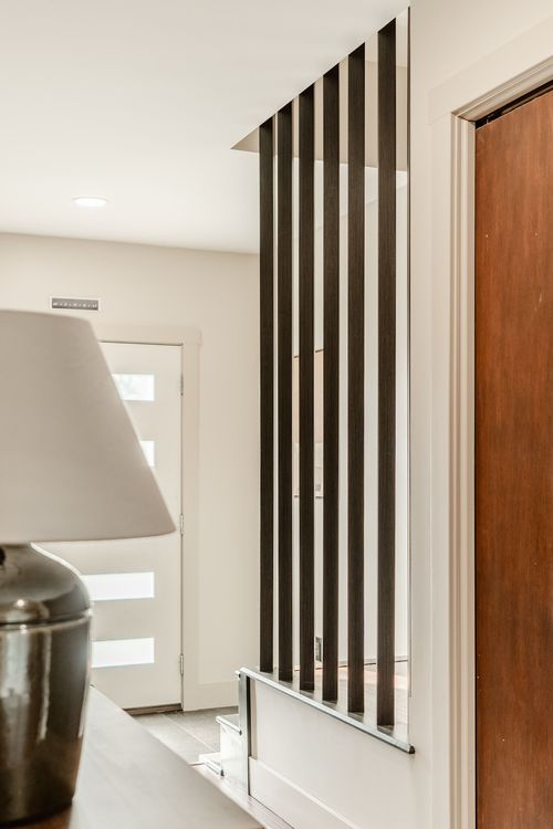 Entryway hallway with a vertical wood slat room divider beside a wooden front door