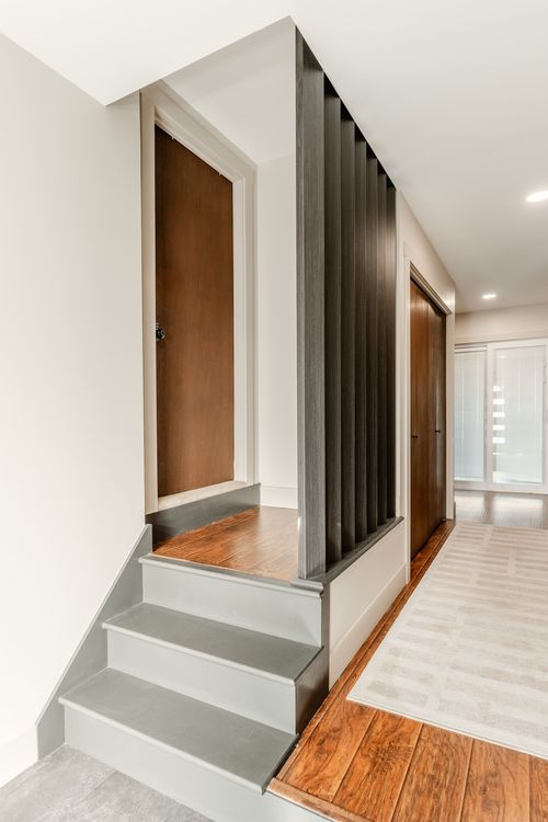 Staircase with wood-tone treads beside paneled doors and a vertical slat partition