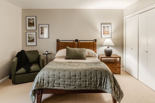 Bedroom with leather headboard, olive quilted bedding and framed art above the bed