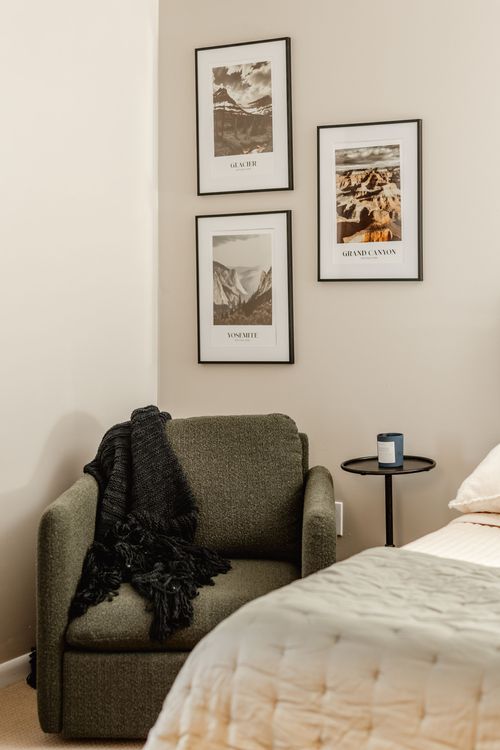 Olive accent chair with black throw beside a round side table and framed national park prints