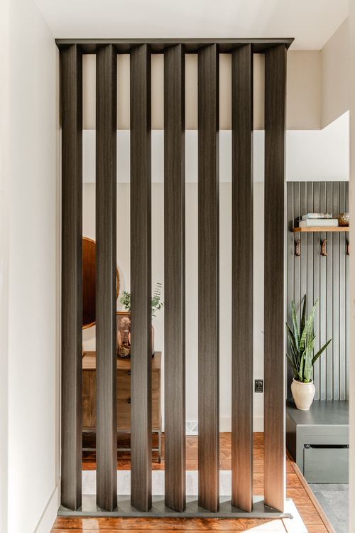 Vertical wood slat screen dividing an entryway from a living space and console table