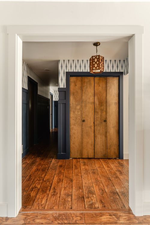 Hallway view of a wood bifold closet door beneath a lattice pendant light