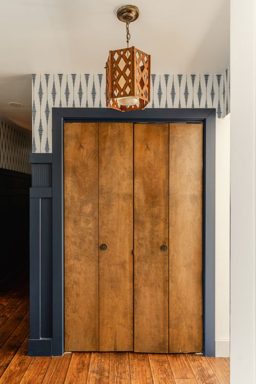 Wood bifold closet doors with a diamond-pattern hanging pendant light above