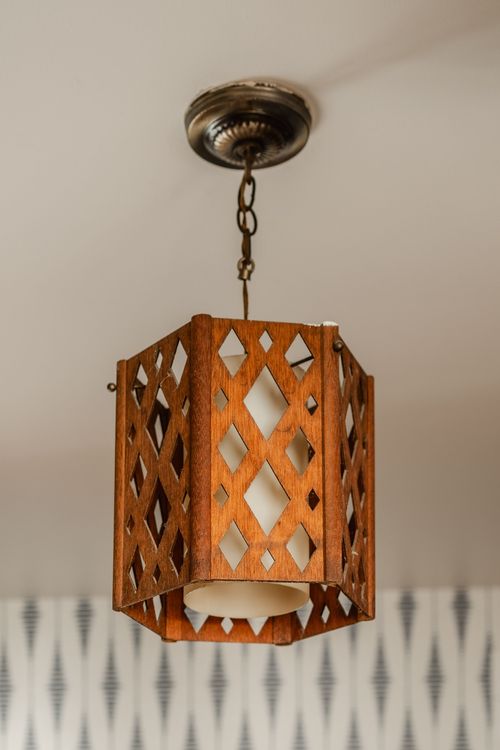 Close-up of a wood lattice pendant light hanging from a brass ceiling mount