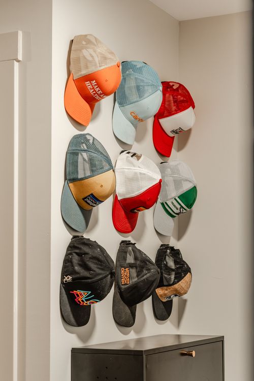 Wall-mounted hat rack displaying an assortment of colorful baseball caps