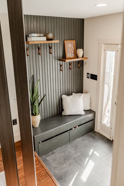Mudroom bench nook with a wood slat wall, floating shelves and coat hooks