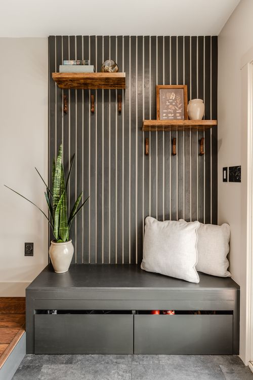 Mudroom nook with a slat wall, floating shelves, snake plant and cushioned bench