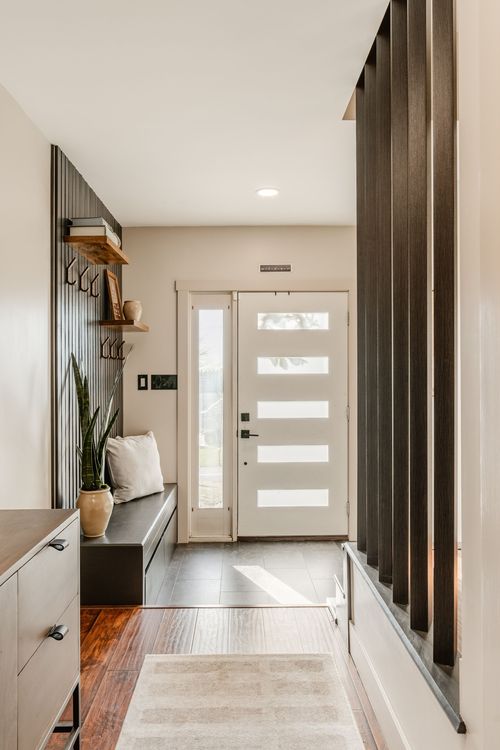 Mudroom entry with a wood slat accent wall, open shelving, bench and glass-paned front door