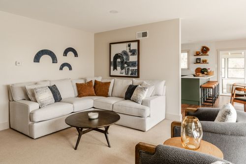Living room with a beige sectional, sculptural black wall art and a round coffee table