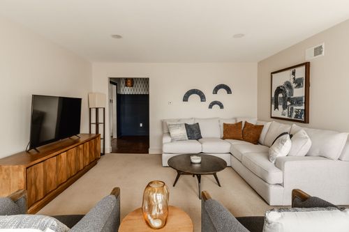 Living room with a wood media console, mounted TV and light gray sectional sofa