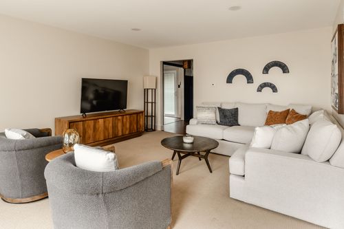 Living room with gray swivel chairs, a wood media console and mounted TV