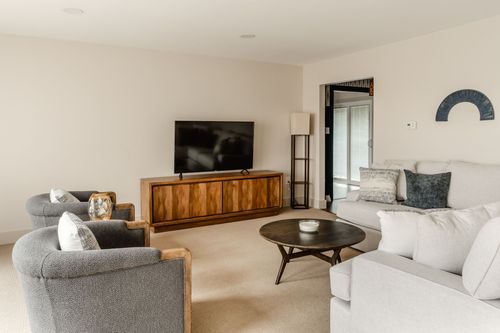 Living room with a wood credenza, mounted TV, floor lamp and swivel accent chairs