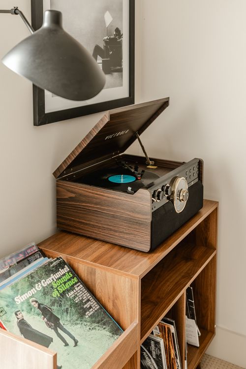 Vintage-style turntable playing a record on a wood cabinet with vinyl storage below