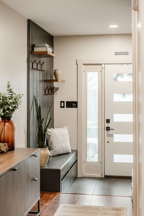 Mudroom bench with a potted snake plant beside a wood slat wall and glass front door