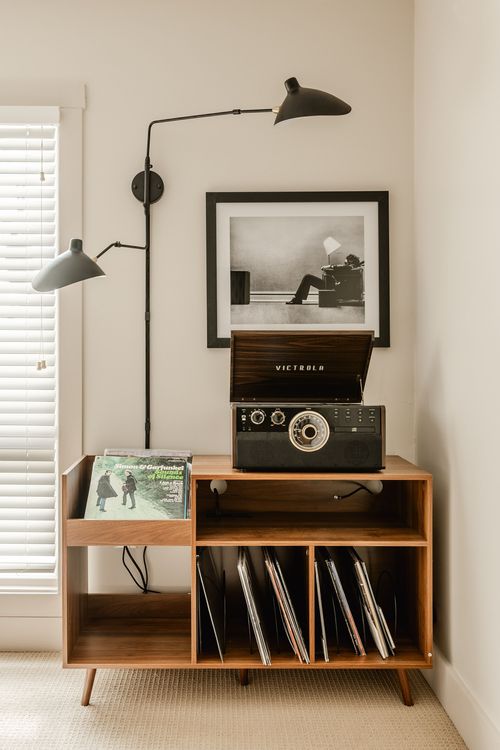 Close-up of a vintage-style turntable with its lid open atop a wood record cabinet