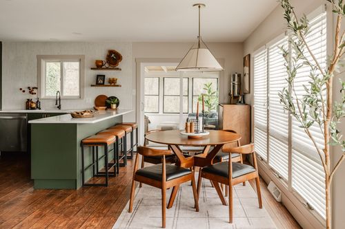 Open kitchen and dining area with green cabinets, wood floors and a round dining table