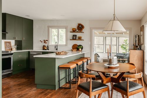 Kitchen with green cabinets, a stainless range and floating shelves with decor