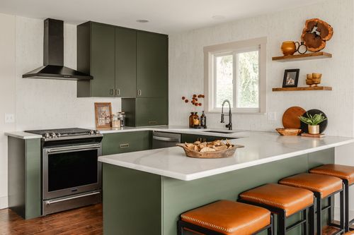 Kitchen with green cabinets, a gas range and open shelving styled with pottery