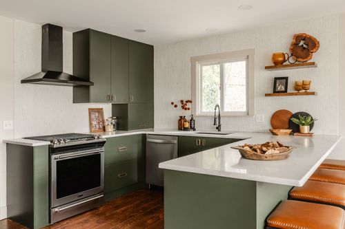 Kitchen with green cabinetry, a waterfall island and leather-topped counter stools