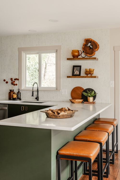 Kitchen island corner with green cabinetry, brass hardware and a marble countertop