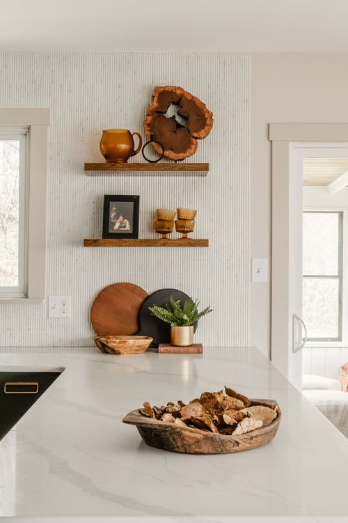 Floating wood shelves styled with amber pottery, a live-edge wood slice and framed photo