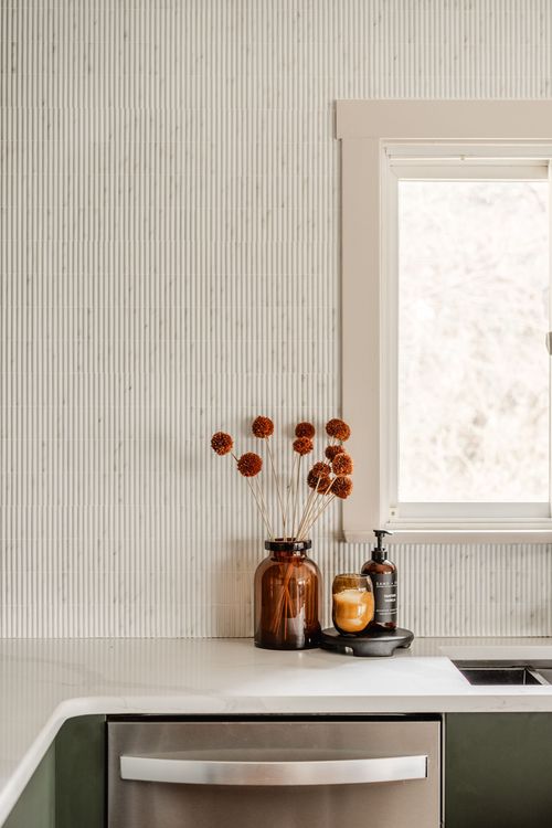 Kitchen counter styled with dried flowers in an amber glass vase beside a window