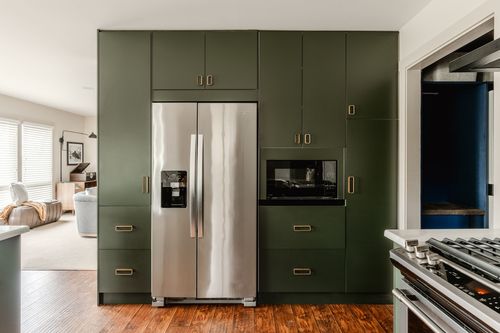 Built-in green cabinetry surrounding a stainless refrigerator and microwave