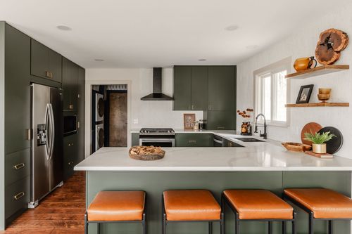 Open kitchen with olive cabinets, white quartz island and orange leather barstools