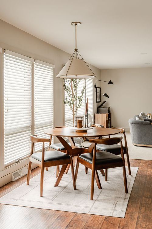 Dining nook with round wood table, black leather chairs and a linen drum pendant light