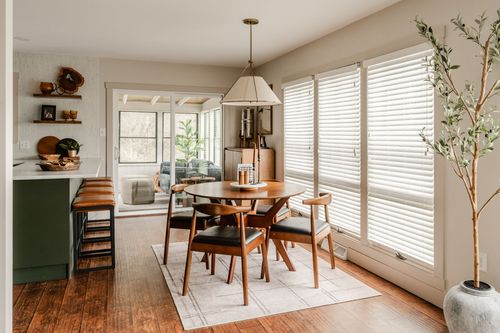 Dining area with mid-century table and chairs opening to a sunroom with wicker basket