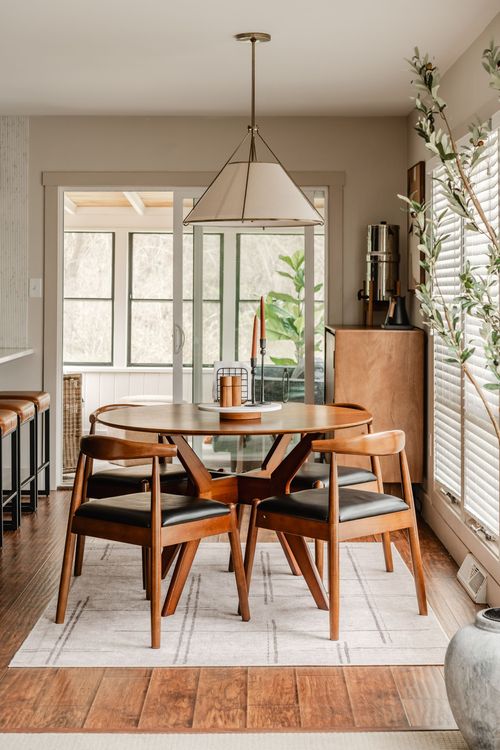Dining table with candle centerpiece near tall windows and an olive branch accent