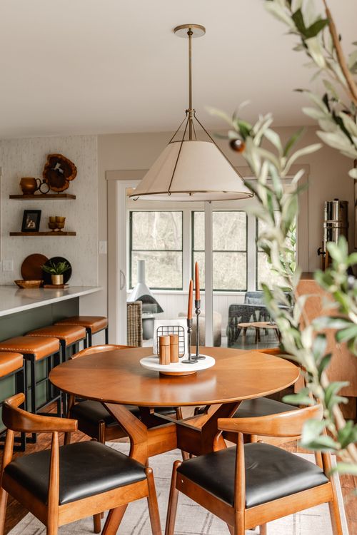 Round dining table set for entertaining beneath a large drum pendant light