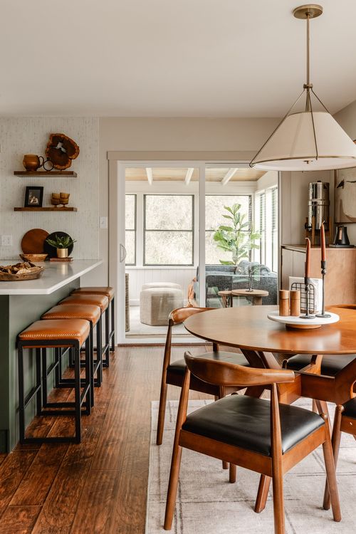 Dining nook with leather barstools, floating shelves and a view into a sunroom