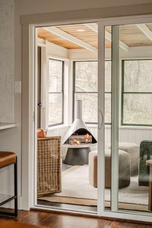 View through sliding glass doors into a screened sunroom with a modern conical fireplace