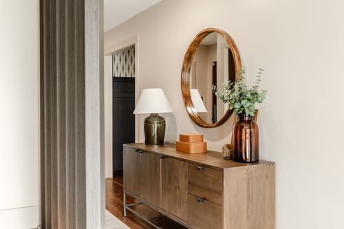 Hallway console table with a round mirror, table lamp and amber glass vase