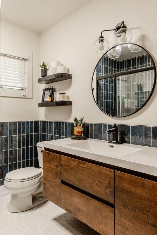 Bathroom vanity with round mirror, black sconce and dark wood cabinetry