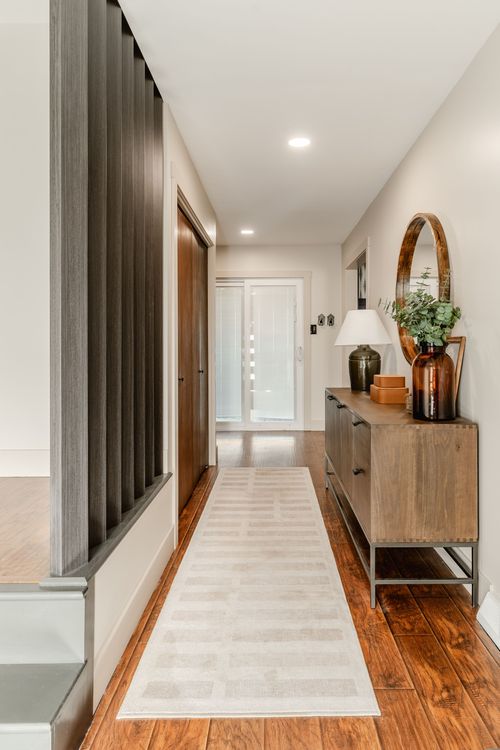 Long hallway runner leading past a wood slat wall to a console table and front door