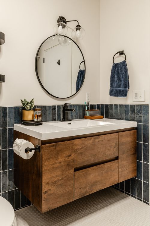 Walk-in shower with dark blue vertical tile and a matte black rain shower fixture