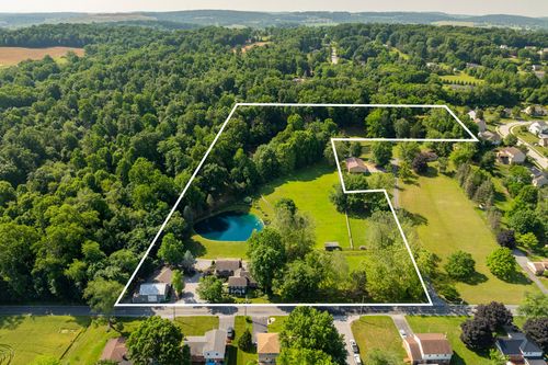 Aerial photo with a white property line overlay outlining wooded acreage around a pond