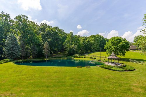 Aerial view of a landscaped pond with a lakeside gazebo and open green lawn