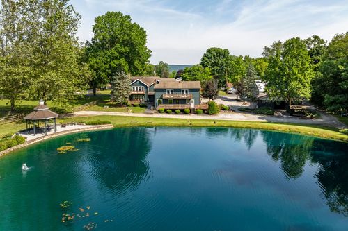 Aerial view of a home overlooking a large pond with a gazebo and manicured grounds