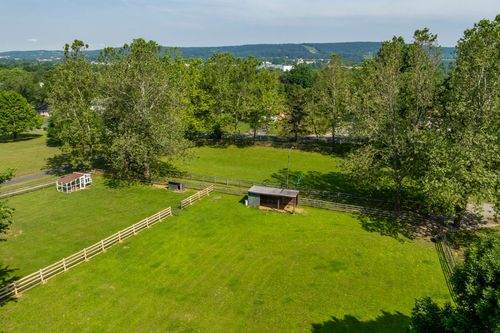 Aerial view of a fenced grassy paddock with a small shed and run-in shelter