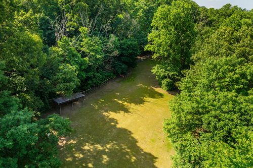 Aerial view of a wooded clearing with a small pavilion structure and open grass path