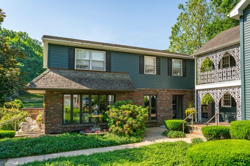 Colonial home exterior with brick addition, ornate iron porch and stone garden wall