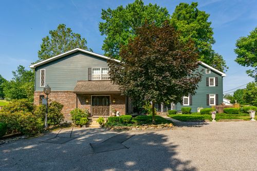 Split-level home with brick and gray siding, a covered entry and stacked-stone landscaping beds