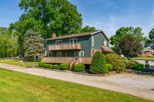 Blue-gray home with a stone chimney and multi-level wood decking overlooking the yard
