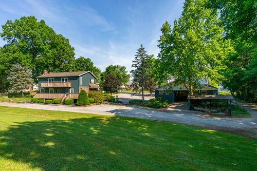 Gray-sided home with a covered deck beside a detached carport and open lawn