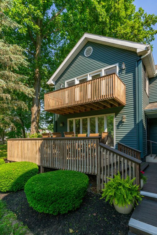 Second-story wood balcony and multi-level deck on a blue-green sided home